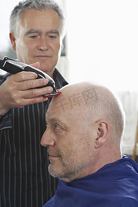 美发师在理发店用头发修剪器剃男顾客的头
