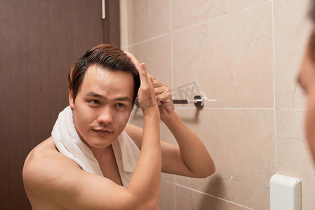 英俊的男人在浴室里梳头的画像。