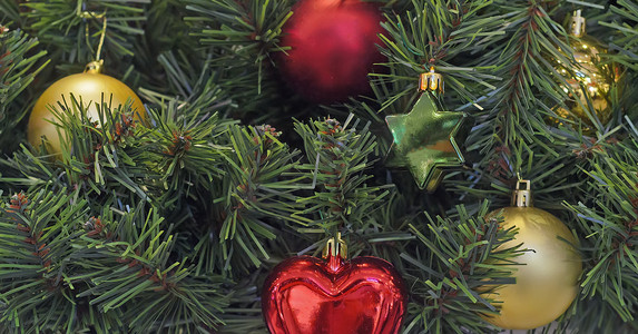星星挂饰摄影照片_圣诞和新年挂饰。五颜六色的圣诞球和树枝背景上的星星玩具。