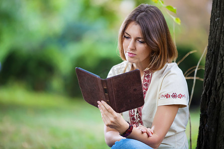 年轻漂亮的女人在公园里看电子书