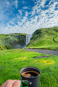 冰岛瀑布摄影照片_在著名的 Skogarfoss 瀑布前制作早晨咖啡，同时在冰岛徒步旅行，夏季，风景优美