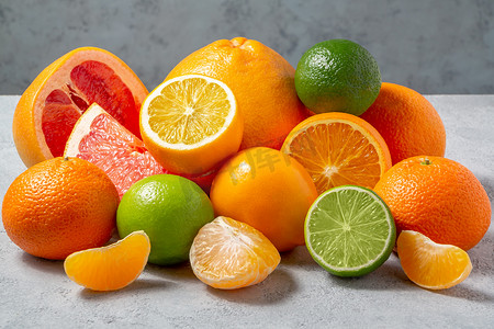 一组完整和切片的柑橘类水果 — 灰色桌子表面的橘子、柠檬、酸橙、橙子、葡萄柚 — 图片