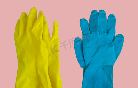 粉红色桌子上黄色和蓝色橡胶防护手套的顶视图，用于春季或日常清洁。