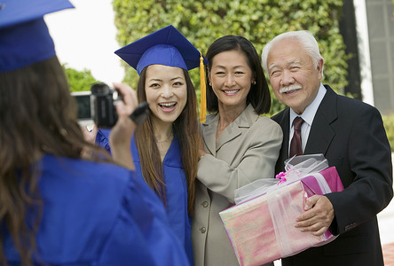 毕业生与母亲和祖父在外面拍摄其他毕业生