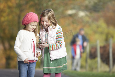 两个小女孩在户外听 MP3 播放器