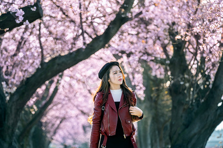 春日在樱花园散步的年轻女子。