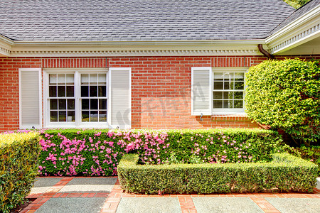 砖红色摄影照片_有英国庭院和白色百叶窗的砖红色房子。