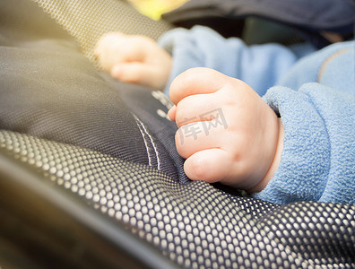 孩子的手握拳，有选择的焦点，孩子在户外散步时在婴儿车里，特写