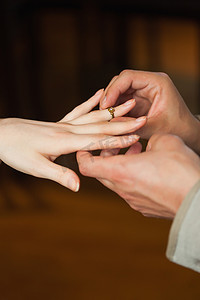 求婚期间男人在未婚夫手指上戴上戒指的特写