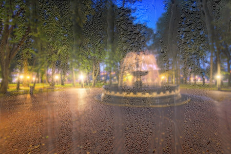 夜间公园里的散焦喷泉，雨后有灯，湿漉漉的