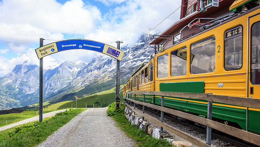 新起点新辉煌摄影照片_从 Kleine Scheidegg 车站开往瑞士格林德瓦尔德的瑞士 wengernalpbahn 铁路列车开始步行小道的起点标志。