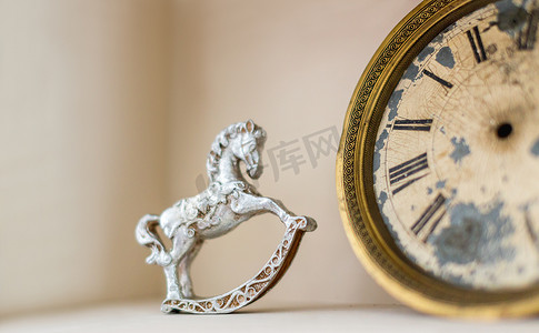 钟表模型摄影照片_书架与古董物品-摇马和复古钟表的老式人物。