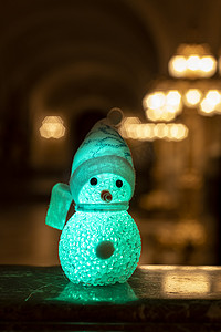 小雪人戴着彩虹围巾和帽子，顶着金色的灯光，等待圣诞节和礼物