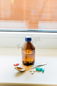 止咳摄影照片_止咳糖浆瓶用勺子靠近窗户