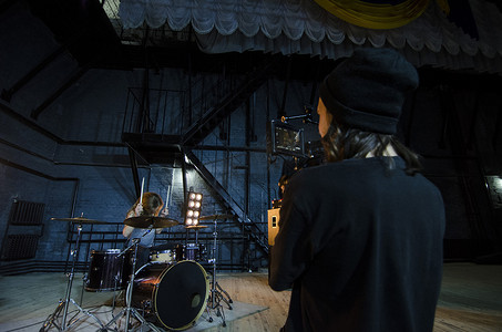 专业摄影师使用电影数码摄像机拍摄音乐视频的鼓手。