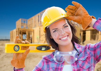 女建筑工人在建筑工地举行水平佩戴手套、安全帽和护目镜。