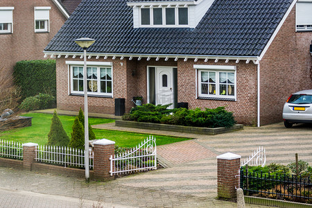 从街景看豪华的荷兰平房，拥有美丽的花园和大门，现代荷兰建筑，位于荷兰的一个小村庄