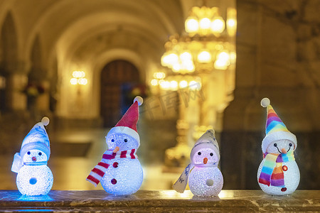 小雪人戴着彩虹围巾和帽子，顶着金色的灯光，等待圣诞节和礼物