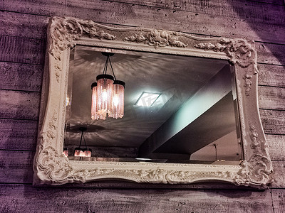木墙上挂着复古风格框架的镜子，在餐厅或酒店的反射中照明