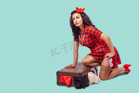 年轻女子坐在地板上，把衣服放在手提箱里
