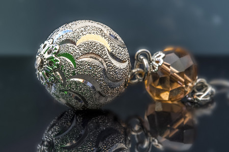 银耳环摄影照片_带琥珀色宝石的银耳环，深色背景，美丽