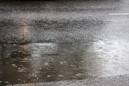 城市雨中沥青路上的水坑，有选择的焦点和博克模糊