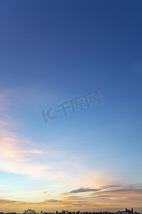 渐变蓝色大气摄影照片_清晨天空的肖像，锡和小云被地平线上生动的早晨日出照亮