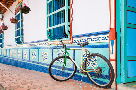 在 Guatape 一座美丽的蓝白相间的房子旁边骑自行车