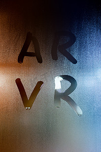 缩写 ar - 增强现实 - 和 vr - 虚拟现实 - 用手指在背景模糊的湿玻璃上书写
