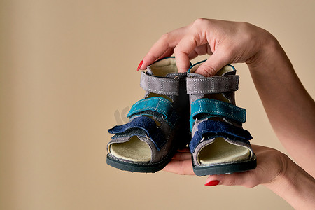 女性拿着一双由真皮制成的特殊儿童矫形鞋凉鞋。