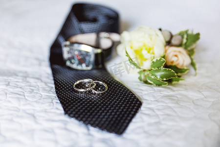 一对金色结婚戒指，黑色领带上镶有钻石。