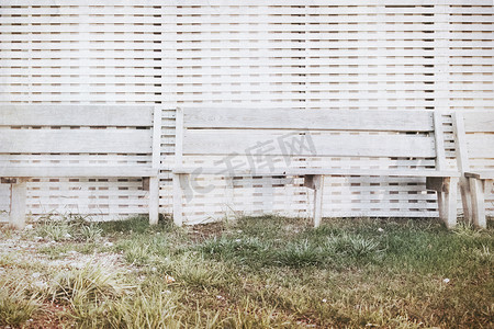 日落时用白色木板站在墙上的长凳