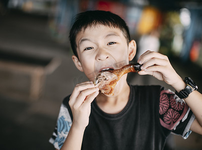 特写兴奋的亚洲男孩吃鸡腿