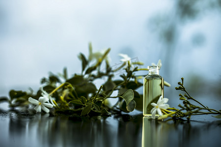 印度茉莉花或 juhi 或 Jasminum Auriculatum 的精华或精油的特写，在一个带生花的小透明玻璃瓶中隔离在白色上。