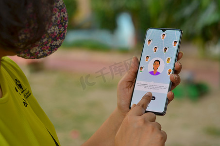 印度德里，2020 年。戴面具的女孩在家庭隔离下在手机上安装 Aarogya Setu 应用程序。