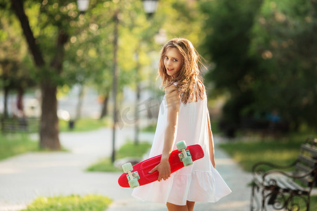 身穿白色连衣裙、带粉红色滑板的可爱都市女孩的画像