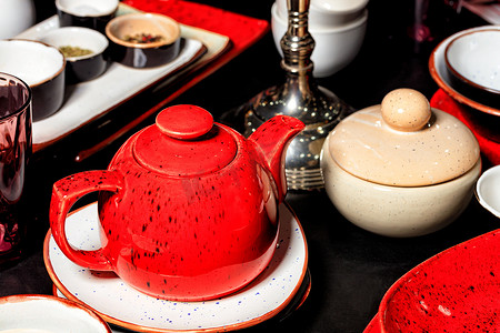 黑桌上的红瓷茶壶和其他茶具。