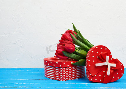 包裹的绿叶摄影照片_一束红色盛开的郁金香，绿叶，包裹的礼物