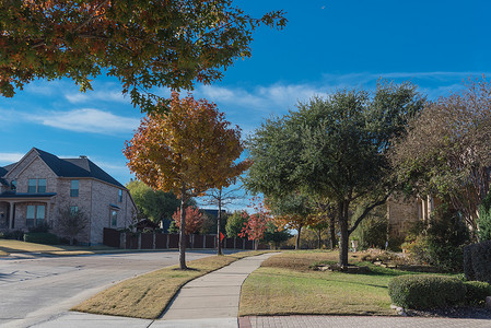 开发区摄影照片_美国得克萨斯州达拉斯附近的人行道上有一排郊区房屋和色彩缤纷的秋叶的相当新的开发区