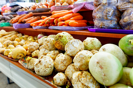 市场货架上出售芹菜、萝卜、胡萝卜、洋葱、根茎和其他各种蔬菜。