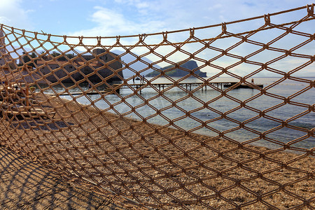 渔网在阳光下晒干，被风吹散，在海岸的映衬下舒展开来。