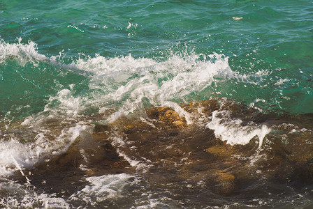美丽清澈的绿松石海水表面照片，海景背景上有波纹和明亮的飞溅，水平图片