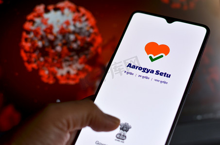 印度新德里，2020 年。Aarogya Setu 应用程序由印度政府开发，用于跟踪 Covid-19 的状态，登录到屏幕前的移动设备上，显示电晕病毒的微观 3D 插图
