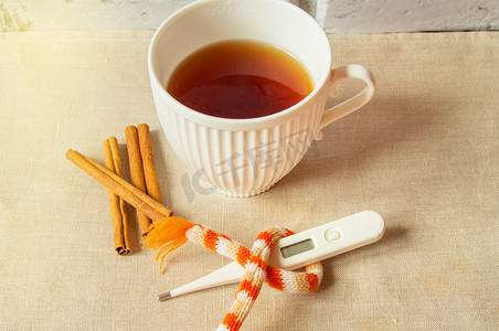 治疗感冒的概念 — 热茶加肉桂、温度计和围巾