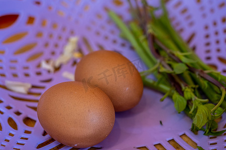 剪鸡蛋摄影照片_紫色篮子里的两个鸡蛋用于烹饪。