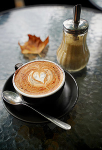 一杯热咖啡拿铁和平白，上面有秋叶