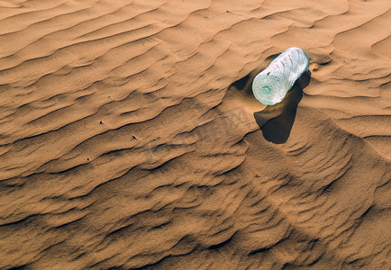 矿泉水瓶摄影照片_沙丘中的矿泉水瓶