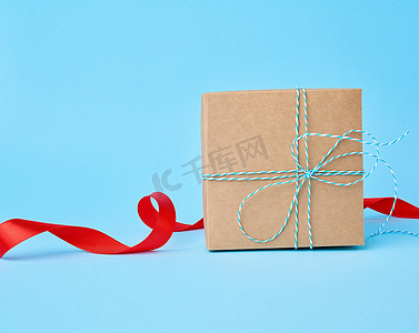 方形棕色纸板盒，用于装礼物和扭曲的丝绸红色丝带