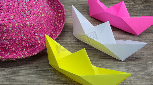 木质背景中的折纸、彩色船和粉色帽子，爱好