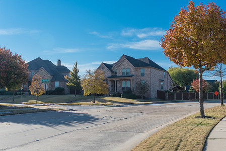 美国得克萨斯州达拉斯附近的人行道上有一排郊区房屋和色彩缤纷的秋叶的相当新的开发区
